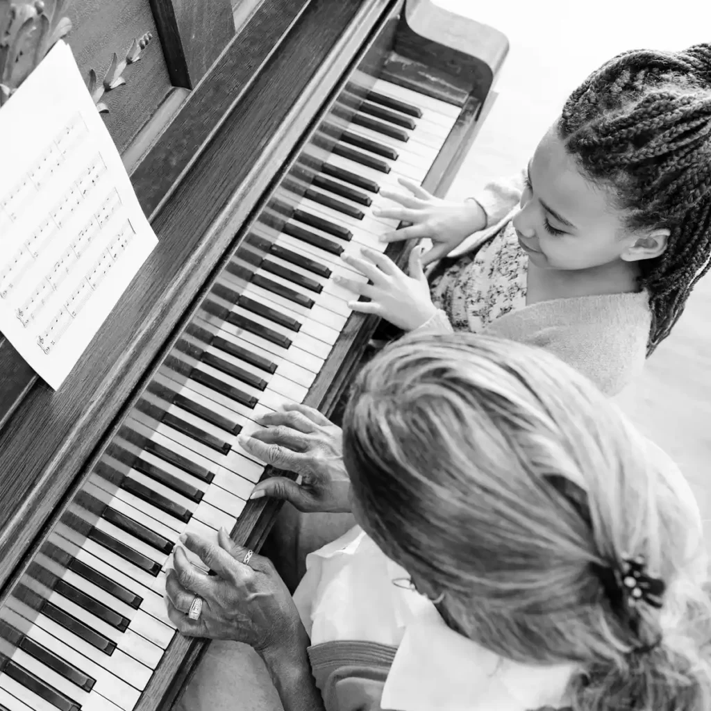 Grandmother and young granddaughter playing piano together