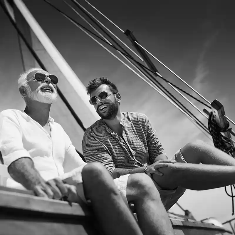 Father and adult son sitting together on a large sailboat