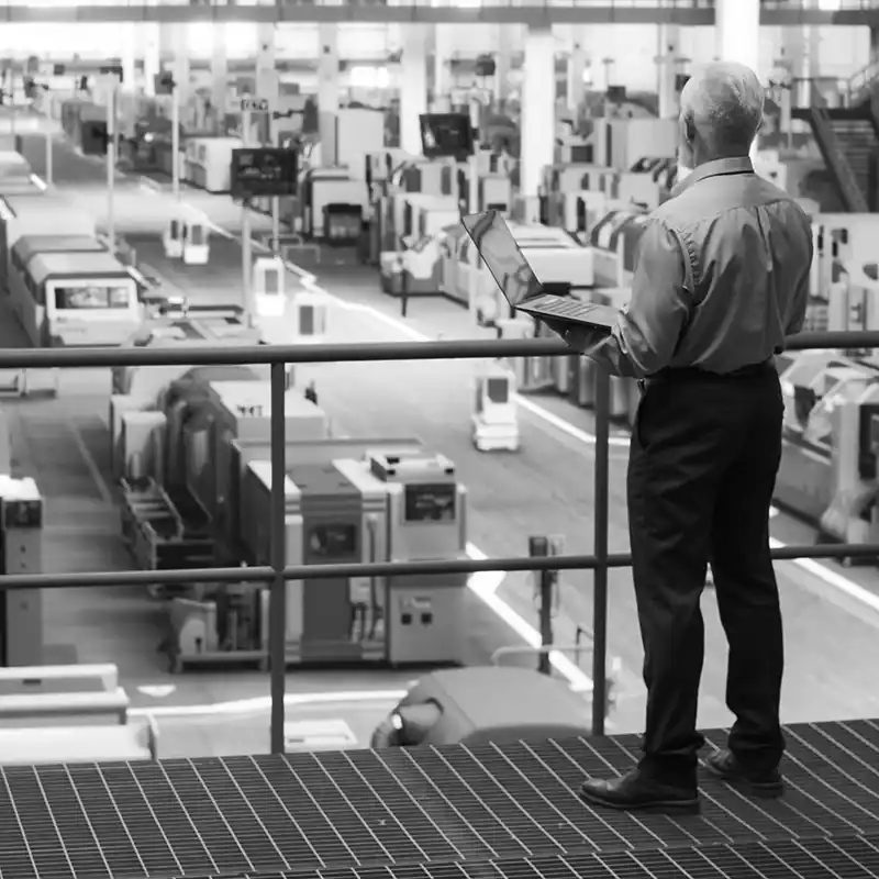 Mature business owner surveying operations from platform inside industrial warehouse